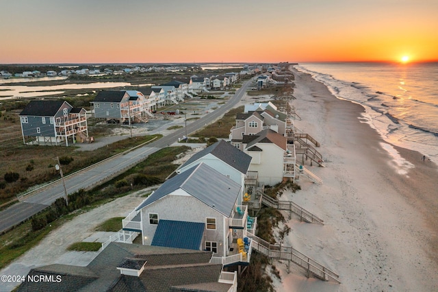 aerial view at dusk featuring a beach view and a water view