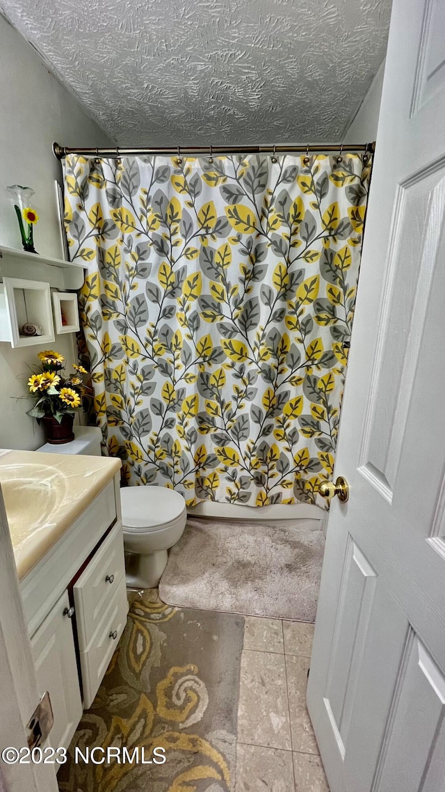 bathroom with toilet, tile flooring, vanity, and a textured ceiling