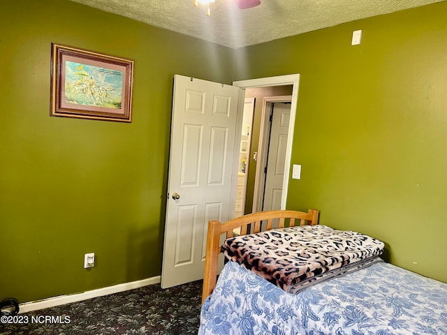 bedroom featuring a textured ceiling, dark colored carpet, and ceiling fan