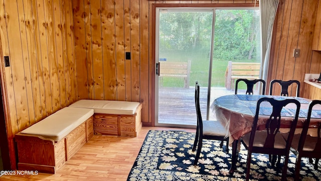 dining room with light hardwood / wood-style flooring and wooden walls