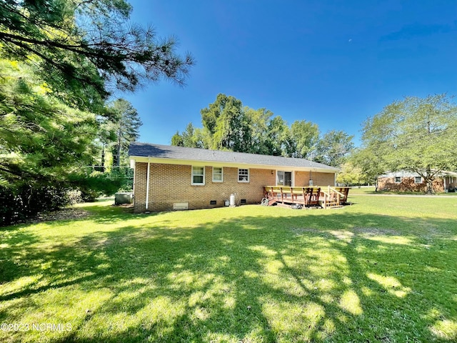 back of property featuring a wooden deck and a lawn