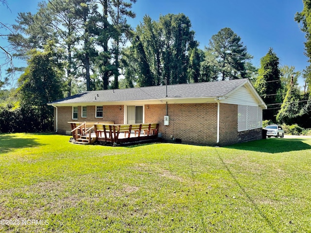 rear view of property with a deck and a yard