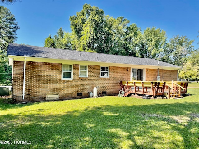 back of property with a deck and a yard