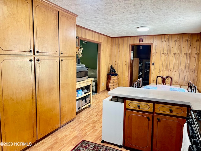 kitchen featuring wooden walls, stove, light hardwood / wood-style floors, and a textured ceiling