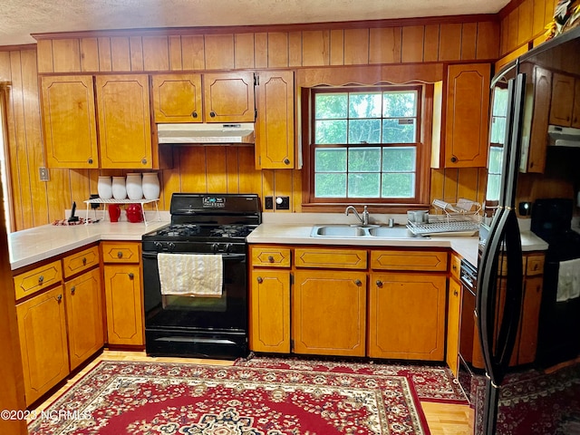 kitchen with ornamental molding, light wood-type flooring, sink, and black gas range oven