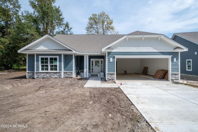 view of front of house with stone siding, an attached garage, and concrete driveway