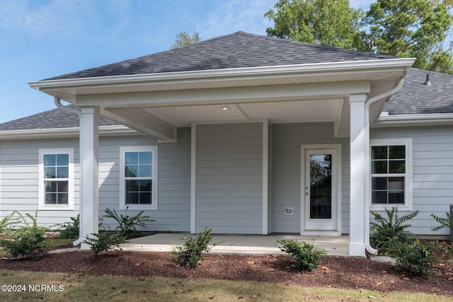 exterior space featuring a porch and a shingled roof