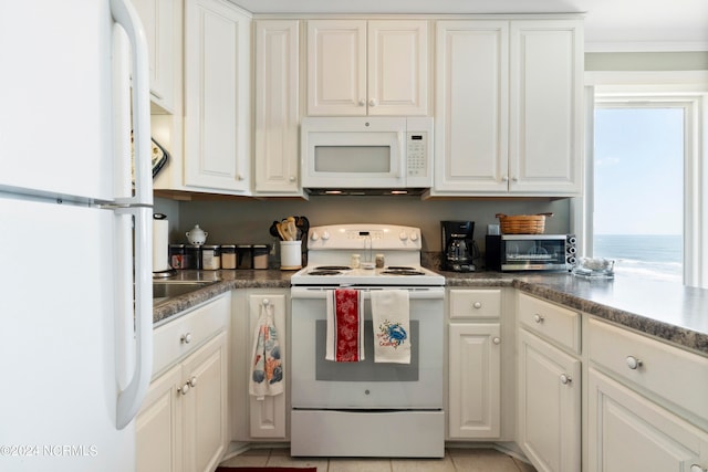 kitchen featuring a water view, white appliances, light tile patterned floors, and white cabinets