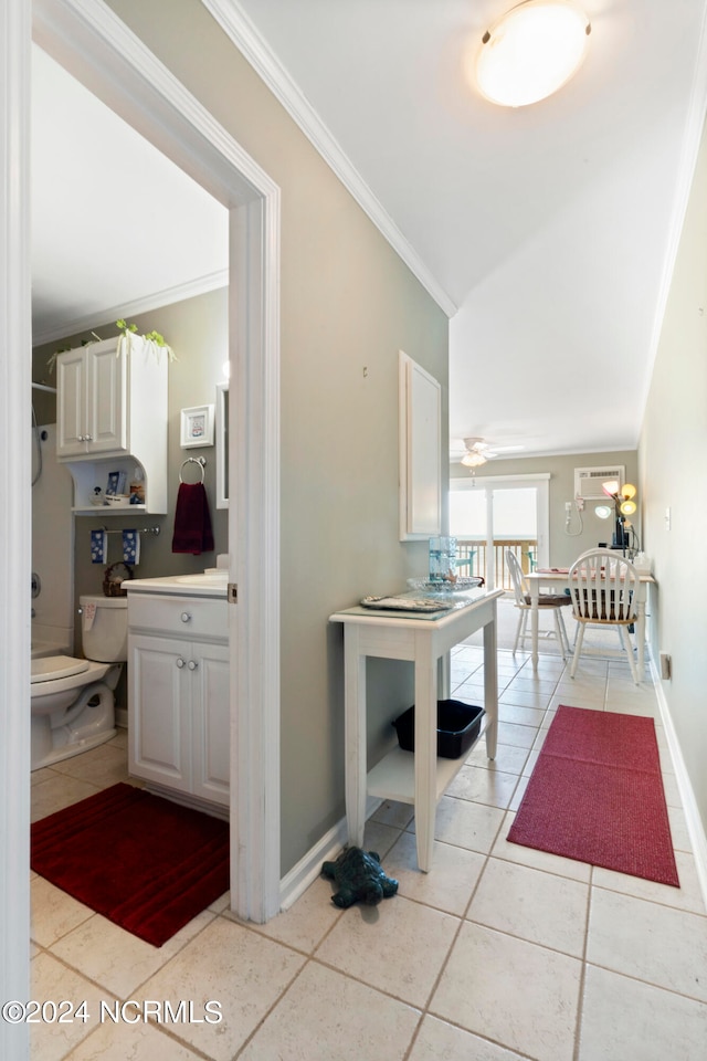 hallway featuring lofted ceiling, ornamental molding, and light tile patterned floors