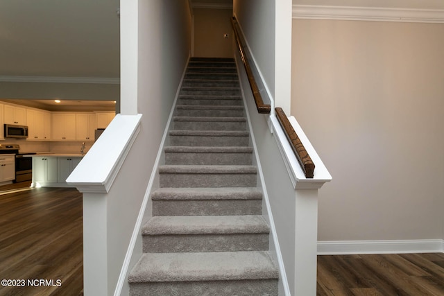 staircase with ornamental molding and dark hardwood / wood-style floors