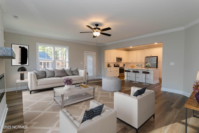 living room with crown molding, light hardwood / wood-style floors, and ceiling fan