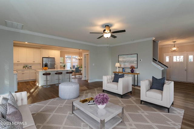 living room featuring hardwood / wood-style flooring, crown molding, and ceiling fan with notable chandelier