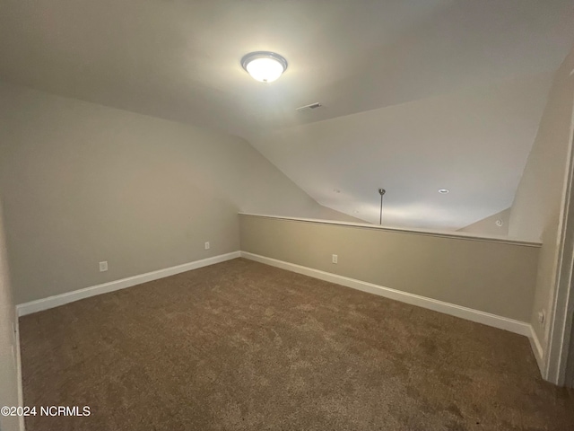 bonus room featuring vaulted ceiling and dark carpet