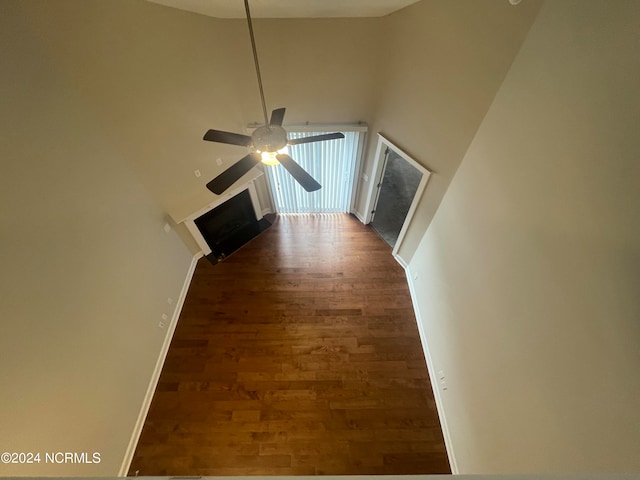 unfurnished living room with ceiling fan, a high ceiling, and dark hardwood / wood-style flooring