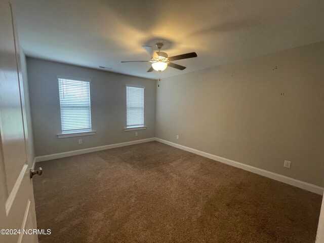 empty room with ceiling fan and dark carpet