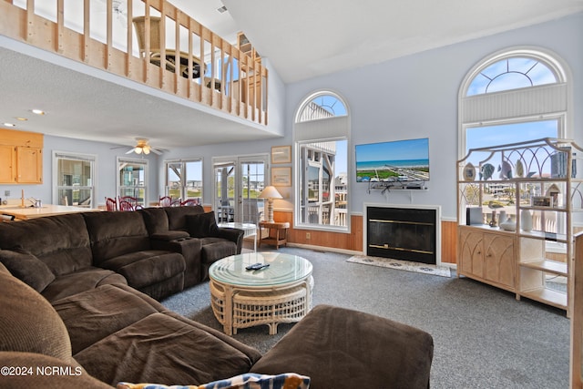 carpeted living room featuring high vaulted ceiling, sink, and ceiling fan