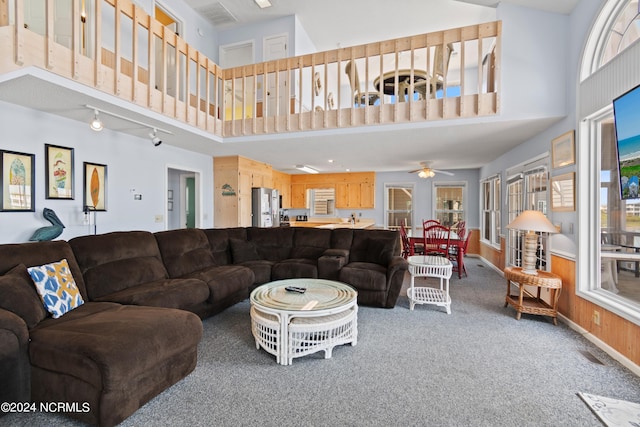 carpeted living room with ceiling fan and a towering ceiling