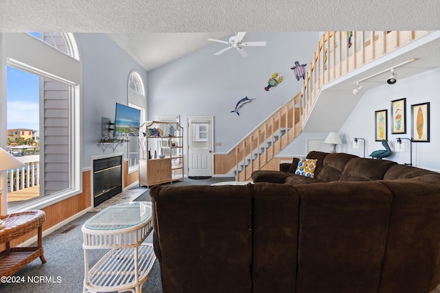 carpeted living room with rail lighting, high vaulted ceiling, ceiling fan, and a textured ceiling