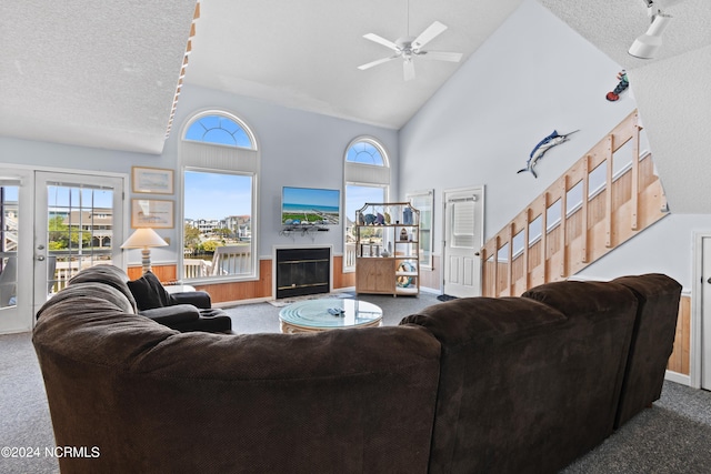 living room with a textured ceiling, high vaulted ceiling, ceiling fan, and carpet