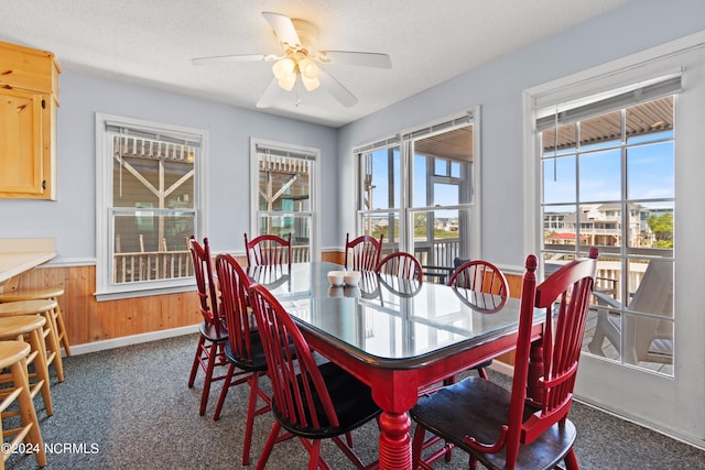 dining area with plenty of natural light, dark carpet, ceiling fan, and a textured ceiling