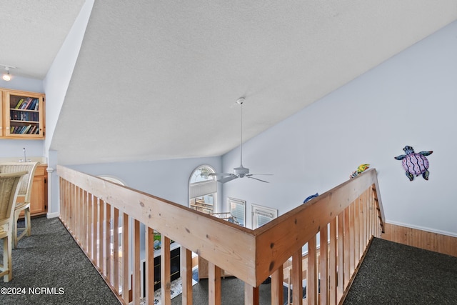 interior space featuring high vaulted ceiling, dark carpet, ceiling fan, and a textured ceiling