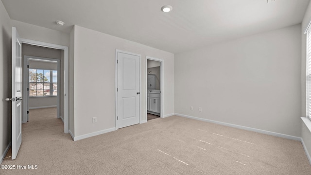 unfurnished bedroom with carpet flooring, ensuite bathroom, and baseboards