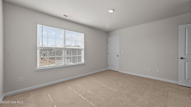 carpeted spare room with visible vents and baseboards