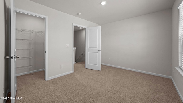 unfurnished bedroom with a walk in closet, baseboards, and carpet floors