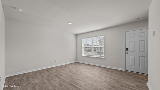 empty room with wood finished floors, visible vents, and baseboards