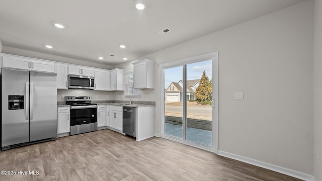 kitchen featuring light stone counters, visible vents, white cabinets, light wood-style floors, and appliances with stainless steel finishes