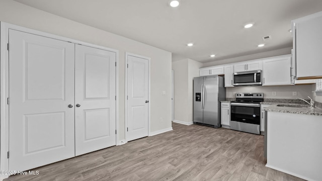 kitchen with recessed lighting, a sink, stainless steel appliances, white cabinets, and light wood-type flooring