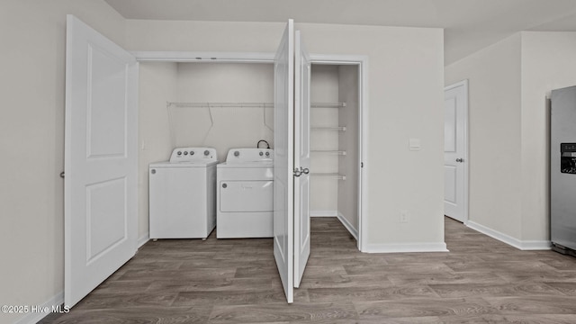 laundry area with laundry area, wood finished floors, baseboards, and washer and clothes dryer