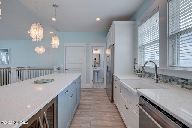 kitchen featuring pendant lighting, stainless steel appliances, white cabinetry, and a notable chandelier