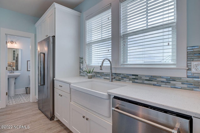 kitchen with appliances with stainless steel finishes, tasteful backsplash, and white cabinets