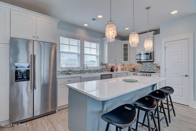 kitchen with sink, appliances with stainless steel finishes, white cabinetry, and a breakfast bar