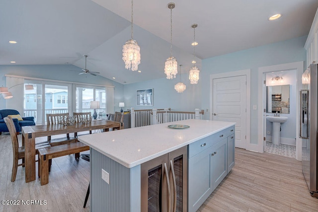 kitchen featuring a center island, ceiling fan with notable chandelier, vaulted ceiling, light hardwood / wood-style flooring, and pendant lighting