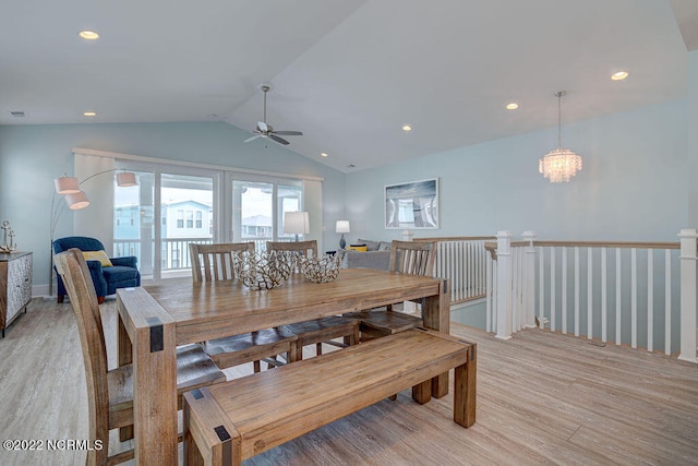 dining area with ceiling fan with notable chandelier, vaulted ceiling, and light wood-type flooring