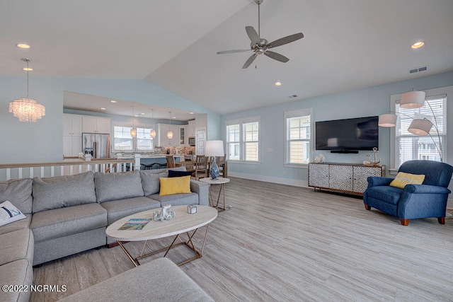 living room featuring ceiling fan with notable chandelier, light hardwood / wood-style flooring, and high vaulted ceiling