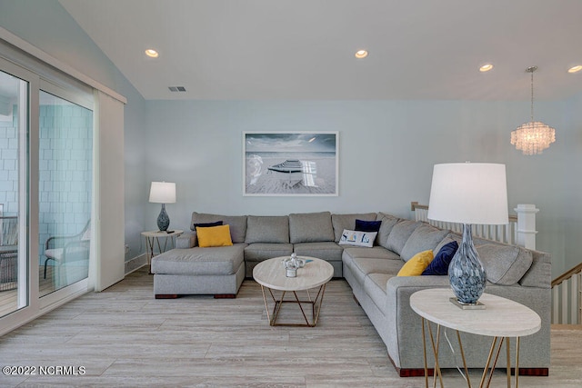 living room featuring vaulted ceiling, light hardwood / wood-style flooring, plenty of natural light, and a notable chandelier