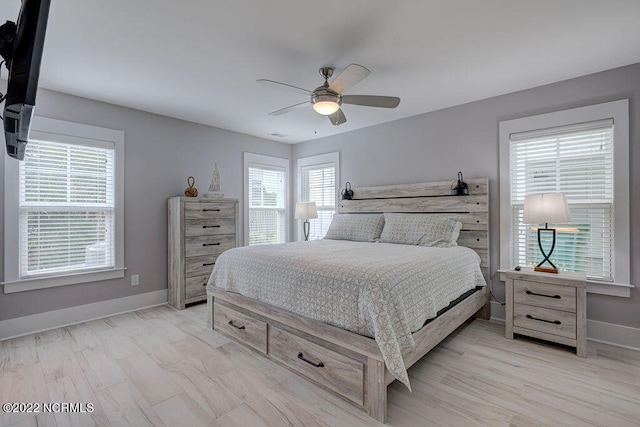 bedroom with light hardwood / wood-style floors, ceiling fan, and multiple windows