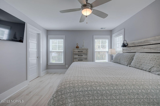 bedroom with ceiling fan, light wood-type flooring, and multiple windows