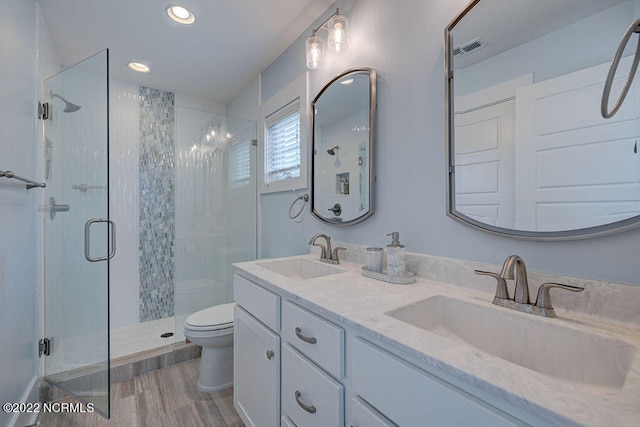 bathroom featuring double vanity, an enclosed shower, and toilet