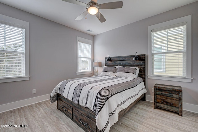 bedroom with light hardwood / wood-style flooring, ceiling fan, and multiple windows