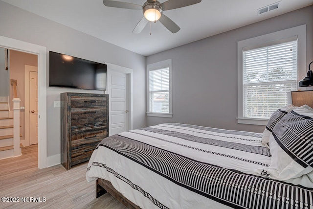 bedroom with light hardwood / wood-style flooring, ceiling fan, and multiple windows