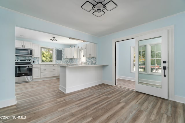 kitchen featuring range, white cabinetry, backsplash, kitchen peninsula, and hardwood / wood-style flooring