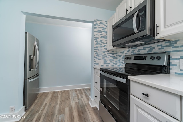 kitchen with white cabinets, light hardwood / wood-style flooring, tasteful backsplash, and stainless steel appliances