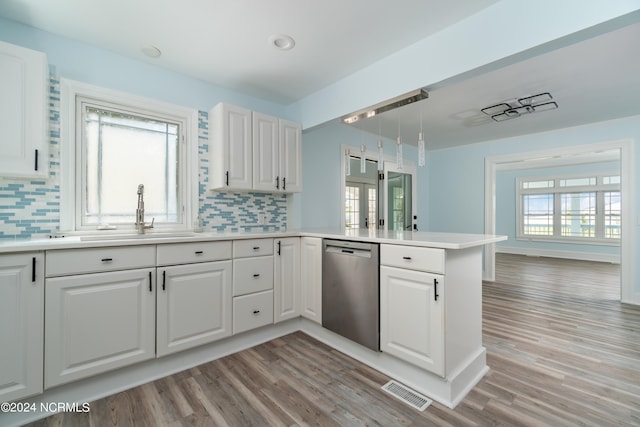 kitchen featuring kitchen peninsula, backsplash, light hardwood / wood-style floors, dishwasher, and white cabinetry