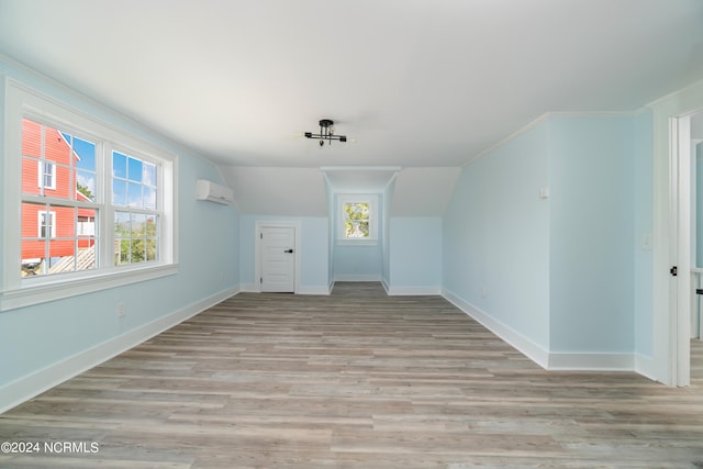 additional living space with plenty of natural light, a wall mounted air conditioner, and light wood-type flooring