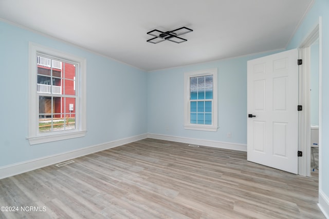 spare room featuring ornamental molding and light hardwood / wood-style flooring