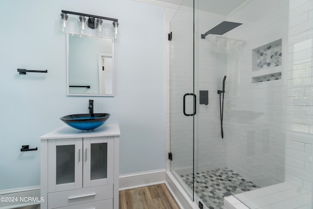 bathroom with crown molding, vanity, hardwood / wood-style floors, and a shower with door